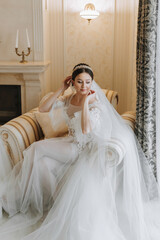 a beautiful girl with a wedding hairstyle in a transparent robe is preparing for a wedding in a hotel with a royal interior.