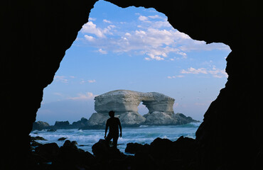 Man silhouetted against La Portada rock arch on the coast of Chile; La Portada, Antofagasta, Chile