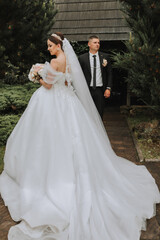 the bride and groom pose against the background of green trees. Wedding walk in nature in the park