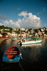 Harbor scene with colorful fishing boats moored close to shore and the port city capital of St Georges in the background on a sunny day; St Georges, Grenada, Caribbean - obrazy, fototapety, plakaty