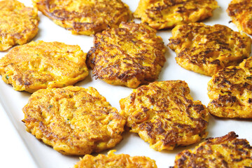 Sweet potato fritters close up. Plant based food. Carrot roasted cutlets with herbs and parsley. Pumpkin crispy fritters or batat fries. Home made sweet potato fluffy pancakes. Vegan food concept.