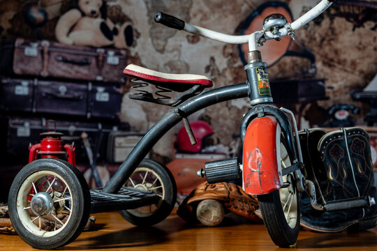 antique children's red tricycle in attic with old toys