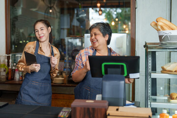 Joy of Asian  elderly mother with daughter Standing to take orders in front of coffee shop, which is their own bakery. Mother's daughter dancing in front of the counter in a good mood that sells well