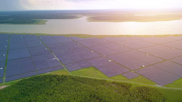 Aerial view of large sustainable electrical power plant with many rows of solar photovoltaic panels in countryside with cloudy sky in Tay Ninh, Vietnam