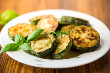 zucchini fried in circles with spices and herbs, in a plate .