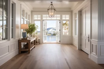 Foto op Canvas A spacious and expansive entryway with a wide interior door, a hallway showcasing a hanging light fixture and transom, adorned in coastal hues, accompanied by an entryway table and beautiful wooden © 2rogan