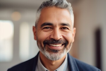 Fototapeta premium Middle aged businessman of arab ethnicity smiling in a modern office and looking at camera