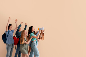 Group of students with megaphone shouting near beige wall