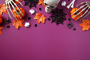 Flat lay Halloween decorations on purple background, top view. Halloween banner mockup with pumpkins, skeleton hands, ghosts, spiders webs, maple leaves on purple background
