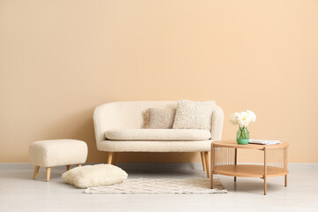 Wooden coffee table with couch and pillows near beige wall
