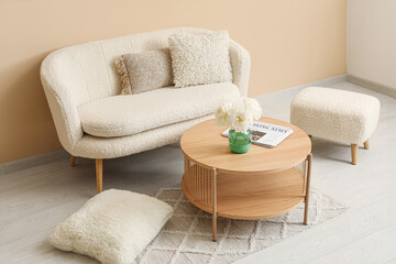 Wooden coffee table with couch and pillows near beige wall