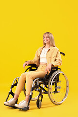 Obraz na płótnie Canvas Young woman in wheelchair on yellow background