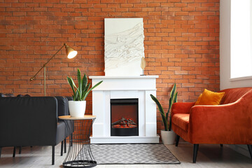 Stylish fireplace, sofa and armchairs near brick wall