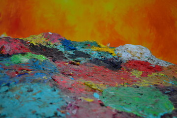 Paleta con pintura al óleo seca en primer plano, contrastando con un fondo amarillo vibrante. 