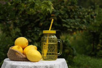 Decanter of Lemonade with a tube of lemons on the background of nature