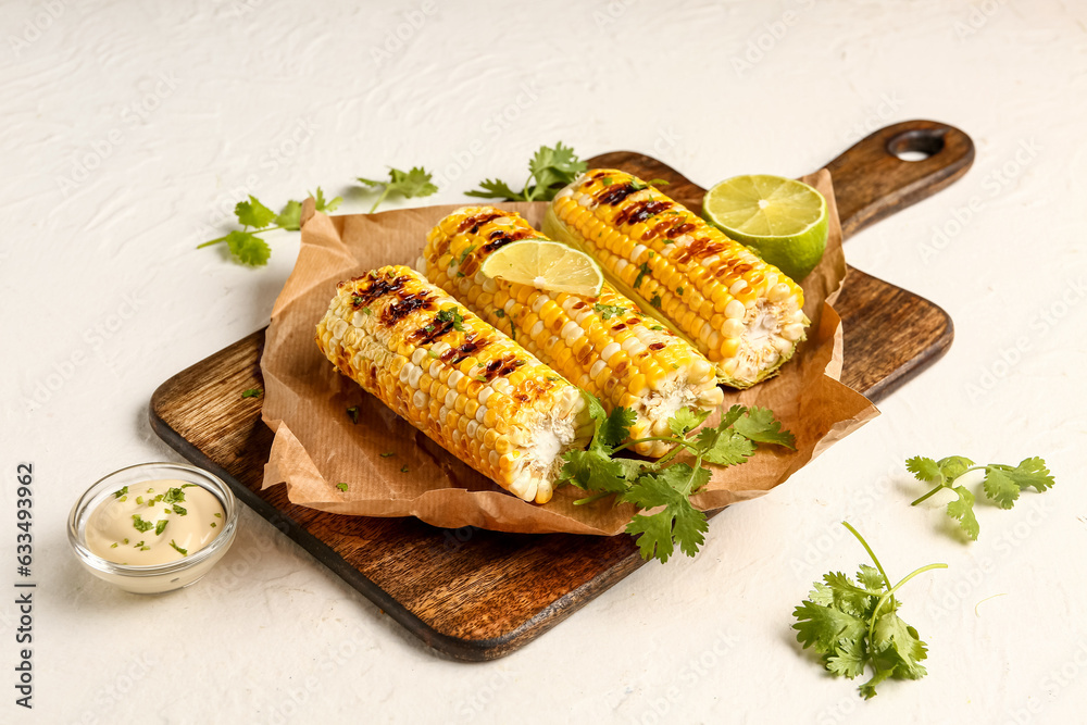 Wall mural baking paper with tasty grilled corn cobs and lime on white background