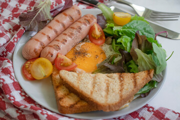 Fried egg with sausages, lettuce, tomato, toast