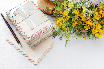 Stack of vintage letters and bouquet of wild flowers on the table.