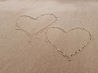 Two hearts drawn on the sand of a sea beach.