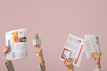 Female hands with newspapers and microphone on color background