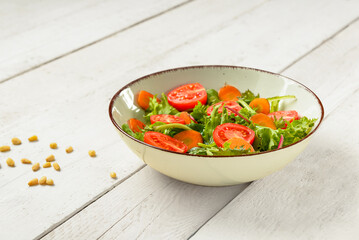 Bowl with fresh vegetable salad on light wooden background