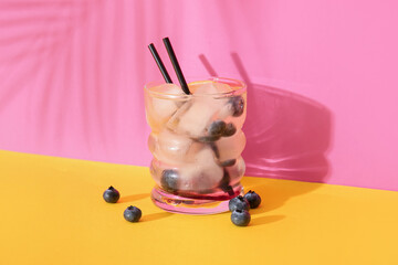 Glass of fresh blueberry lemonade on colorful background