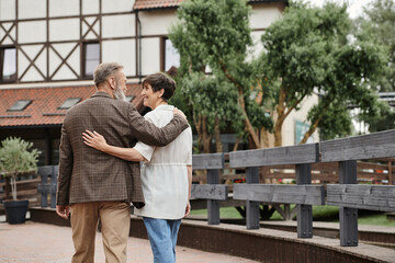 Obraz premium happy and elderly man and woman hugging and walking together outdoors, senior couple, romance