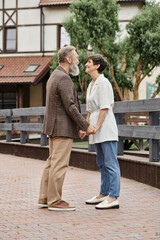 Fototapeta na wymiar woman and bearded man holding hands, date, senior romance, happy elderly couple, full length