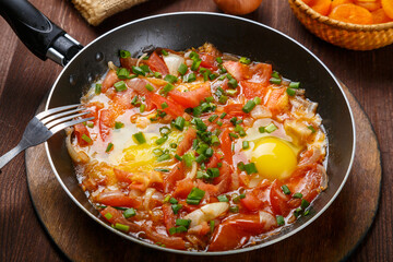fresh shakshuka in a frying pan sprinkled with green onions on a laid Shabbat table.
