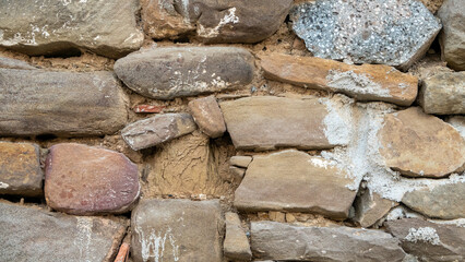 old stone wall background in various colors. The wall of the old historical stone house built with stones one by one