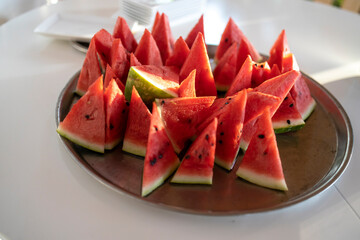 Lots of small triangular slices of ripe red watermelon on a plate. Isolated on white background. View from above