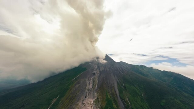 Aerial view active volcano eruption with smoke stream disaster natural gas flow high mountain seismology. FPV sport drone shot volcanic erupting geology formation cone crater cliff rock with misty fog