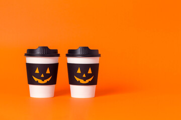 Two halloween coffee cup on orange background. Poster for cafe with copy space.