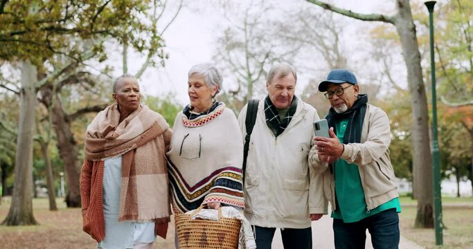 Phone, picnic and elderly people walking in the park together in the morning during retirement. Nature, spring and wellness with senior friends browsing social media outdoor in a garden for bonding