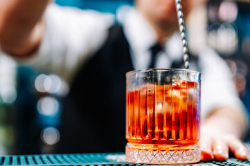 man bartender hand making negroni cocktail. Negroni classic cocktail and gin short drink with sweet vermouth, red bitter liqueur
