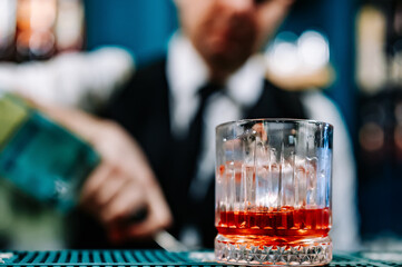 man bartender hand making negroni cocktail. Negroni classic cocktail and gin short drink with sweet vermouth, red bitter liqueur