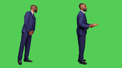 Male office worker in formal suit waiting in studio, looking around over full body green screen. Startup employee feeling confident and stylish on camera, greenscreen background.