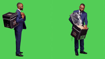 Male takeout employee in suit having meal order, carrying thermal bag with fast food. Deliveryman being stylish and confident delivering takeaway food, full body greenscreen backdrop.