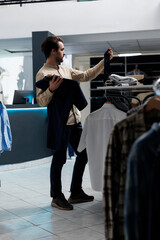 Clothing store customer selecting tie and shirt while shopping for formal outfit. Young man...