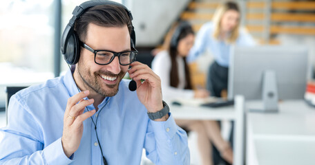 Portrait of smiling bearded call center operator man sitting at workplace. Call center concept