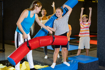 Team of friends playing with inflatable sticks in indoor amusement park