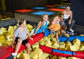 Playful happy children friends spending time together infront of foam rubber pit in trampoline game...