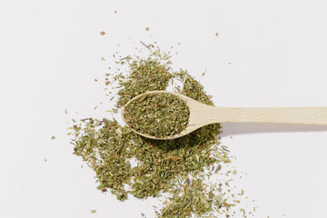 Dried and crushed oregano herb spice in a wooden spoon on a white background. The concept of aromatically prepared dishes, improving the taste with spices