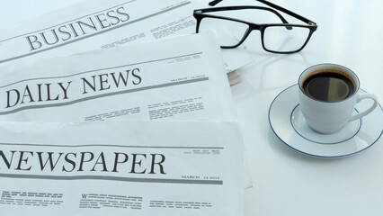 eyeglasses and newspapers on the white desk 