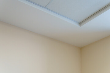 Fototapeta premium Parts of the ceiling decor in the corner, suspended ceiling made of white gypsum slabs. Modern office design.