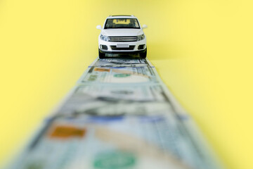 White toy car on money road on yellow background