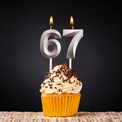 birthday cupcake with number 67 candle - Celebration on dark background