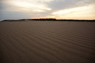 Arena en el médano con atardecer de fondo