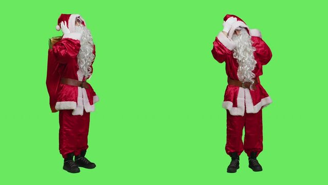 Santa claus being sick with headache, feeling unwell during christmas holidays on full body greenscreen. Young man wearing seasonal red costume, suffering from painful migraine.