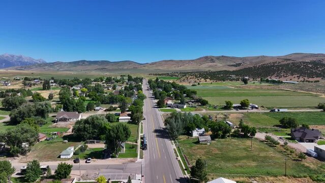 Rural mountain town main street Utah pull. Farming community agricultural economy. Spring summer weather mountain valley green agriculture field. Homes, barns and buildings.